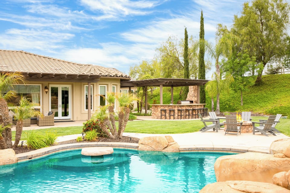 The private entertainer's backyard features a pool, hot tub, and plenty of lounge spaces to enjoy the outdoors.