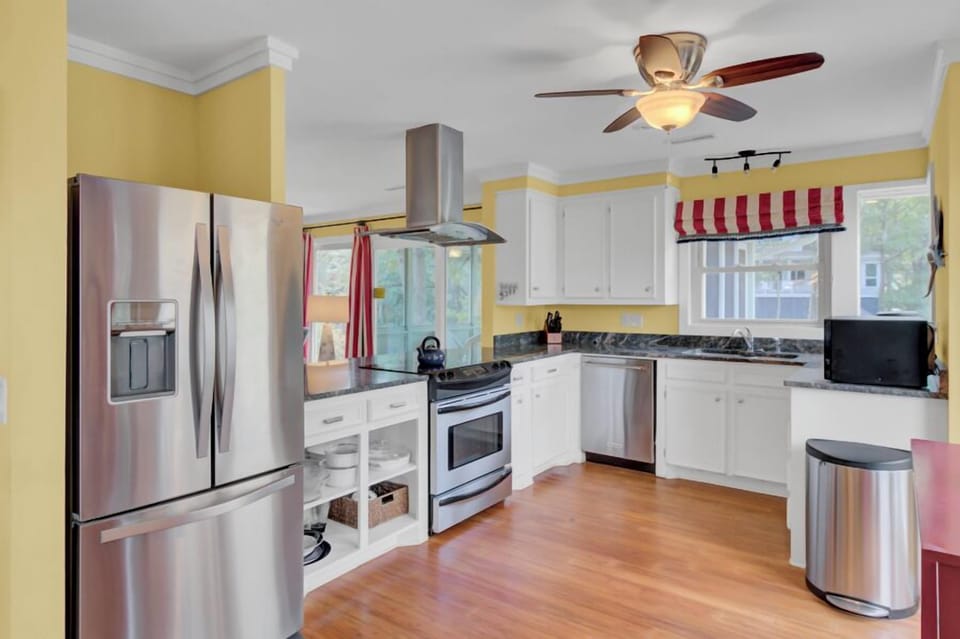 Your fully equipped kitchen awaits with stainless steel appliances, granite countertops, and cheerful yellow walls creating the perfect space for home-cooked meals.