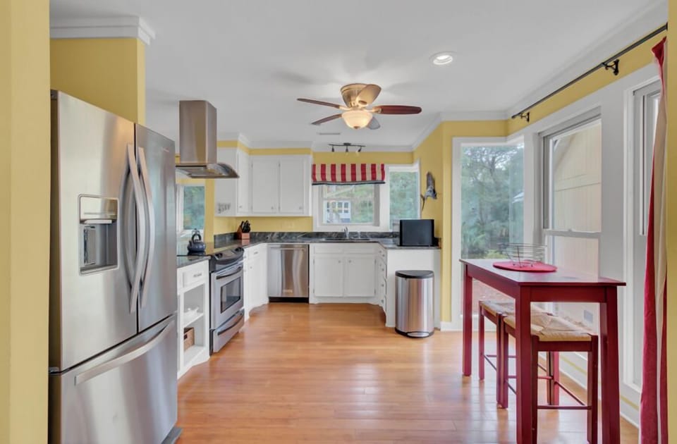 Gather in your bright, fully-equipped kitchen featuring stainless steel appliances, white cabinetry, and warm wood floors perfect for morning coffee.