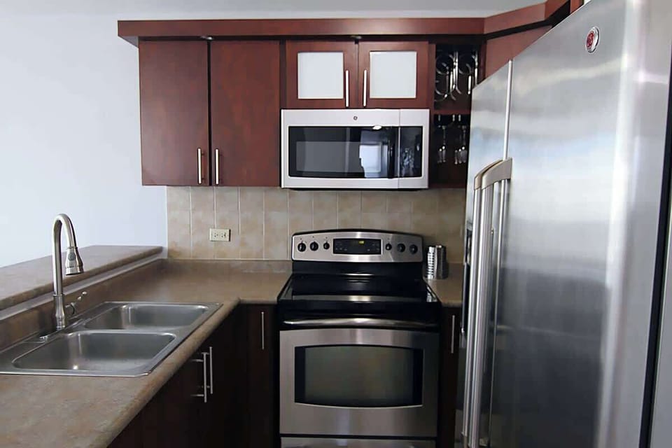 Fully equipped kitchen featuring a refrigerator, stove with oven, microwave, coffee maker, toaster, blender, and complete sets of pots, pans, utensils, silverware, cups, mugs, and plates.