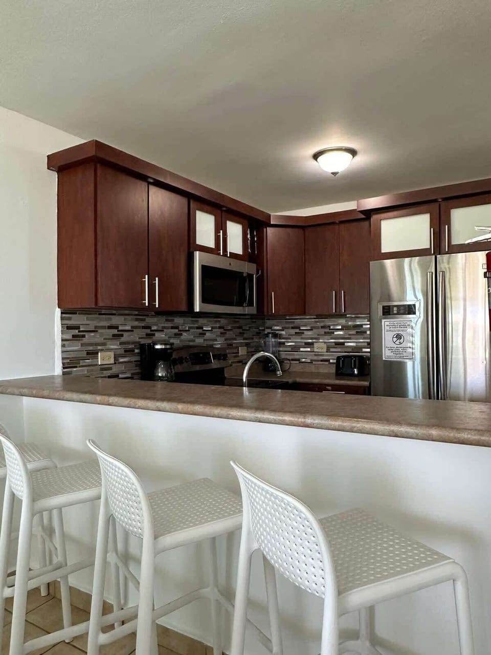 Fully equipped kitchen featuring a refrigerator, stove with oven, microwave, coffee maker, toaster, blender, and complete sets of pots, pans, utensils, silverware, cups, mugs, and plates.