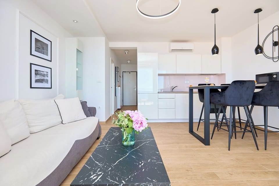 Step into a bright, open-plan living space with sleek modern furnishings and a fully equipped kitchen, designed for comfort and style.