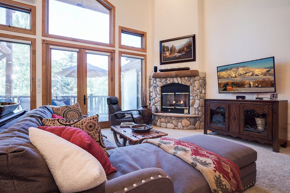 Cozy up in your mountain retreat with plush seating, crackling stone fireplace, and stunning views through floor-to-ceiling windows.