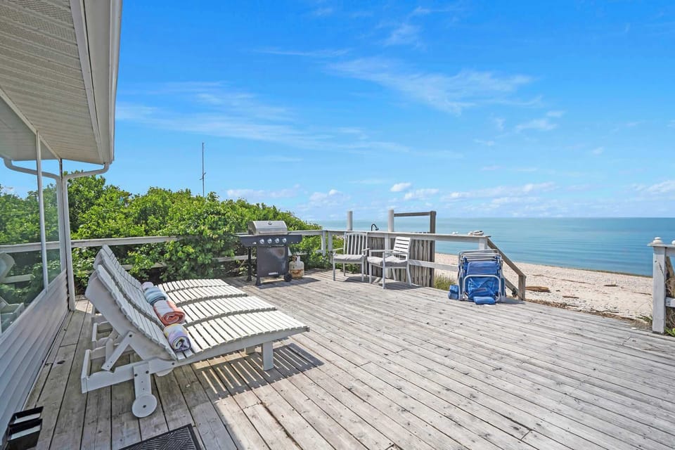 Waterfront deck with grill and lounge seating.