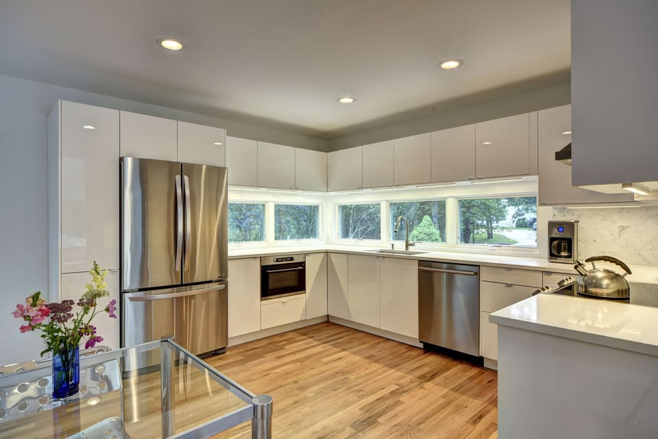 Modern, European-style kitchen with quartz counter tops and marble back splash.