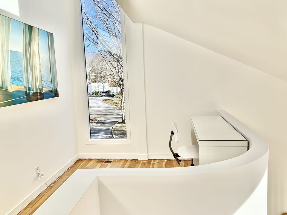 Sunny workspace with desk, chair, and outlet on second floor landing.
