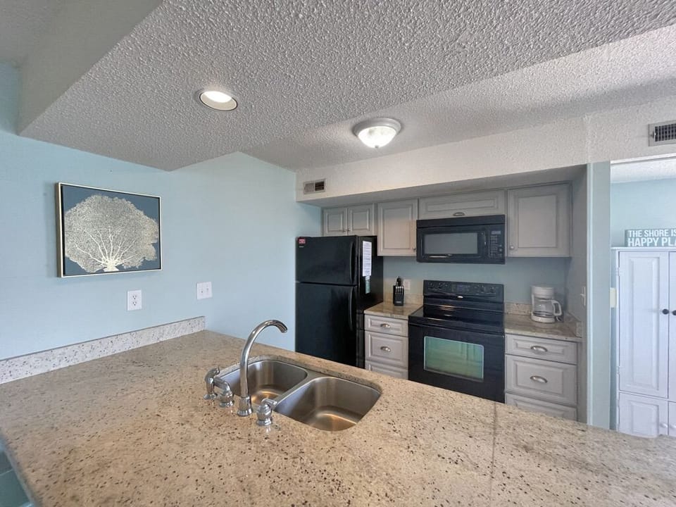Kitchen has dishes, plated, drip coffee brewer, baking dishes and pans. 