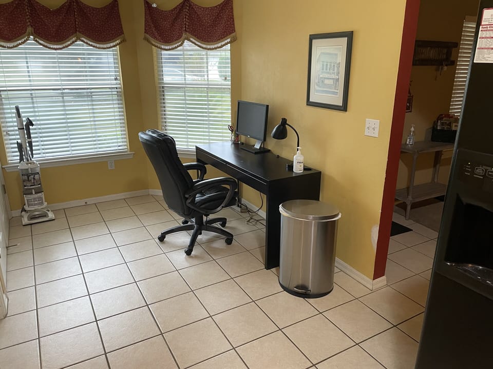 Office area with desk, office chair, lamp, monitor and miscellaneous supplies