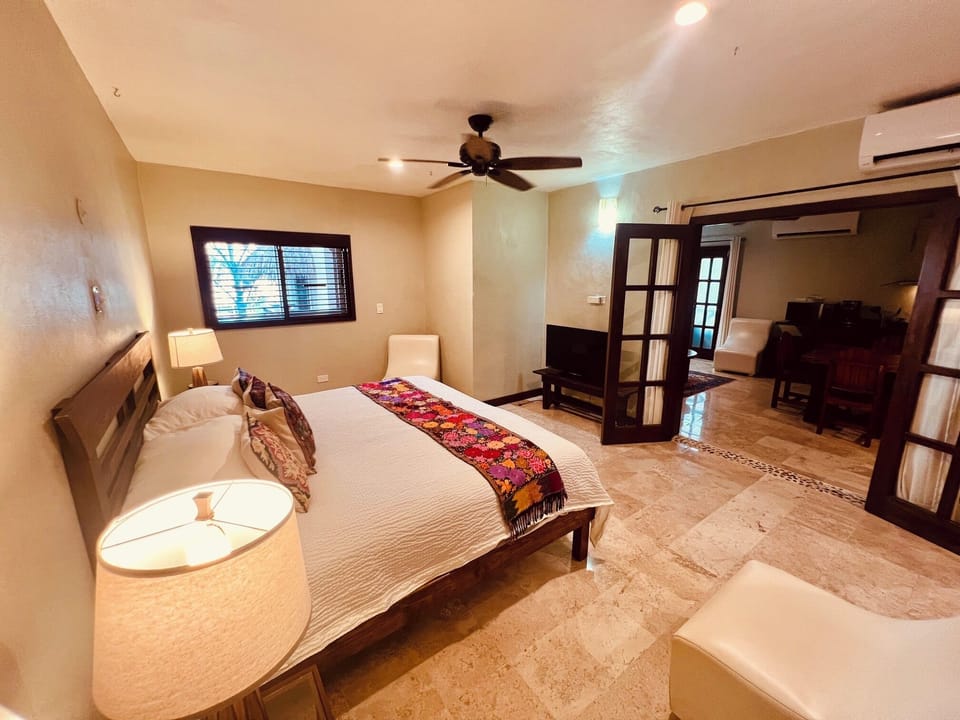 Full suite guest room with a king bed, warm lighting, and open living area