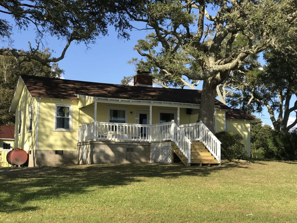A Cottage with a View has a grassy yard amidst shady live oaks.