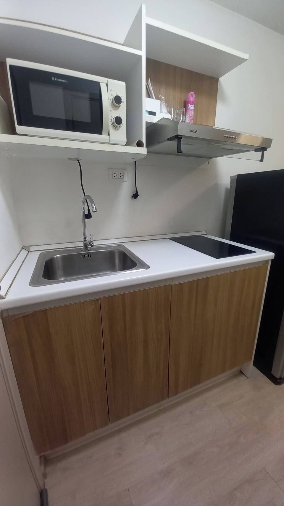 Kitchen with stove and vent, microwave, and full sized refrigerator.