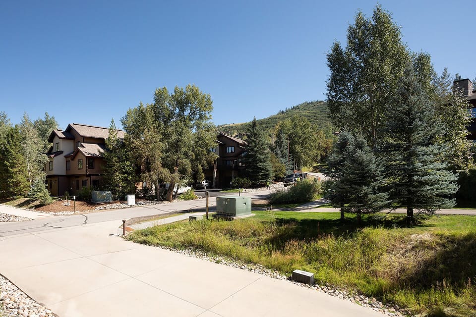 Peaceful mountain neighborhood setting with mature trees and well-maintained pathways leading to the property entrance.