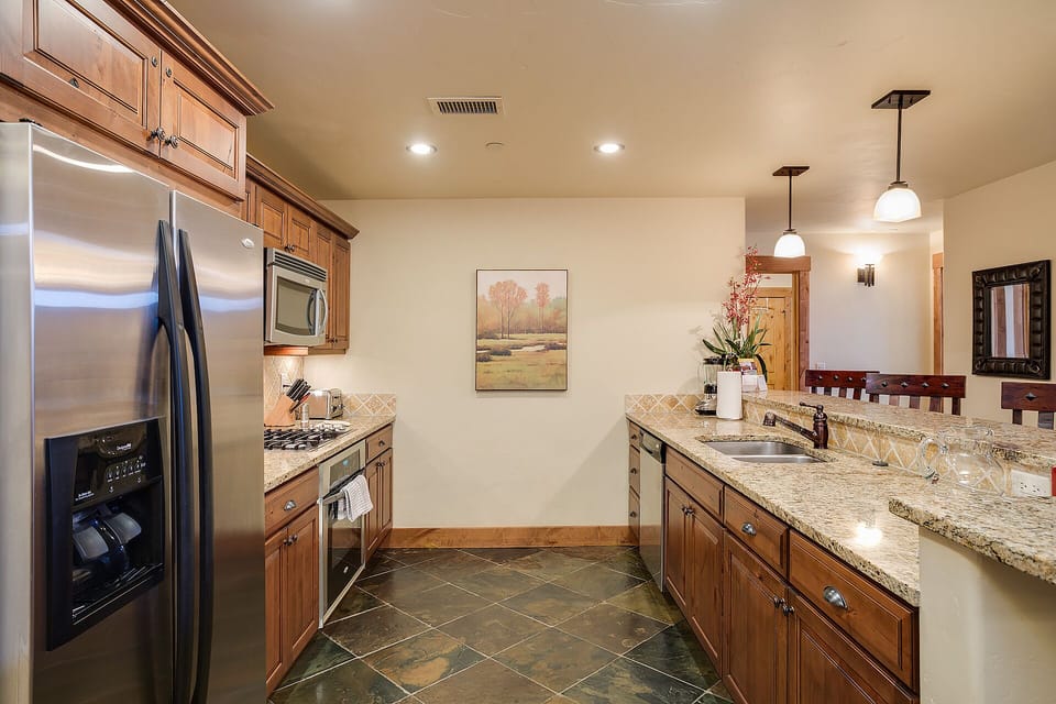 Your gourmet kitchen features granite countertops, stainless steel appliances, and warm wood cabinetry perfect for preparing memorable meals together.