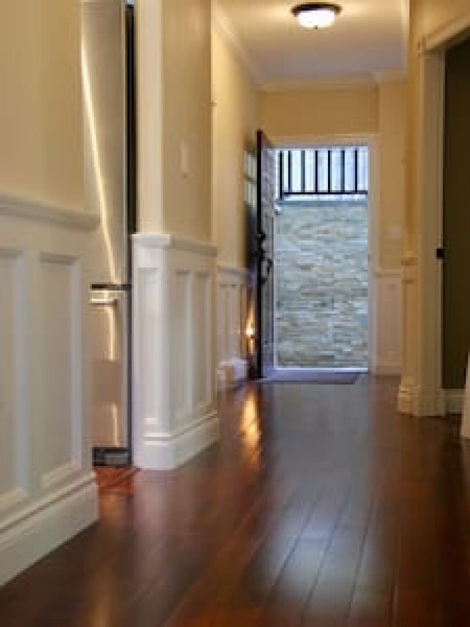 High ceilings, charming wainscotting looking at the door entranceway.e