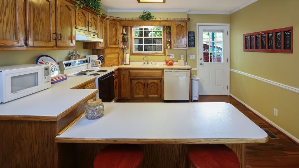 Fully furnished kitchen with oven, dishwasher, garbage disposal, and coffee pot.