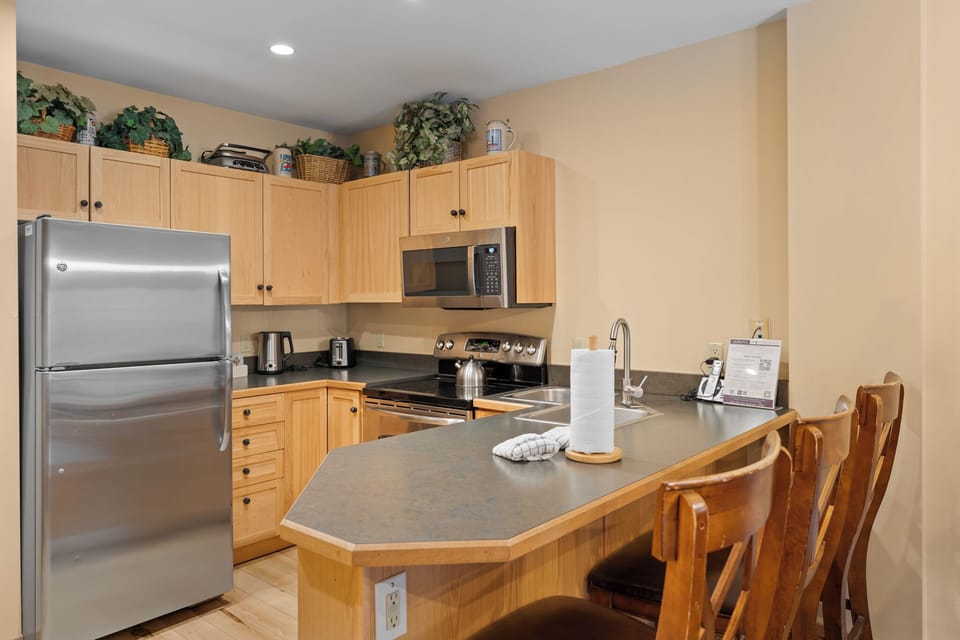 Full kitchen with stainless steel appliances and breakfast bar with seating for 3