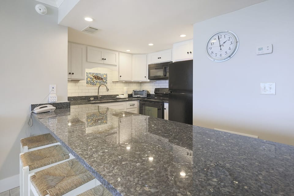 This kitchen features sleek black appliances, granite countertops, and a stylish backsplash, perfect for culinary adventures