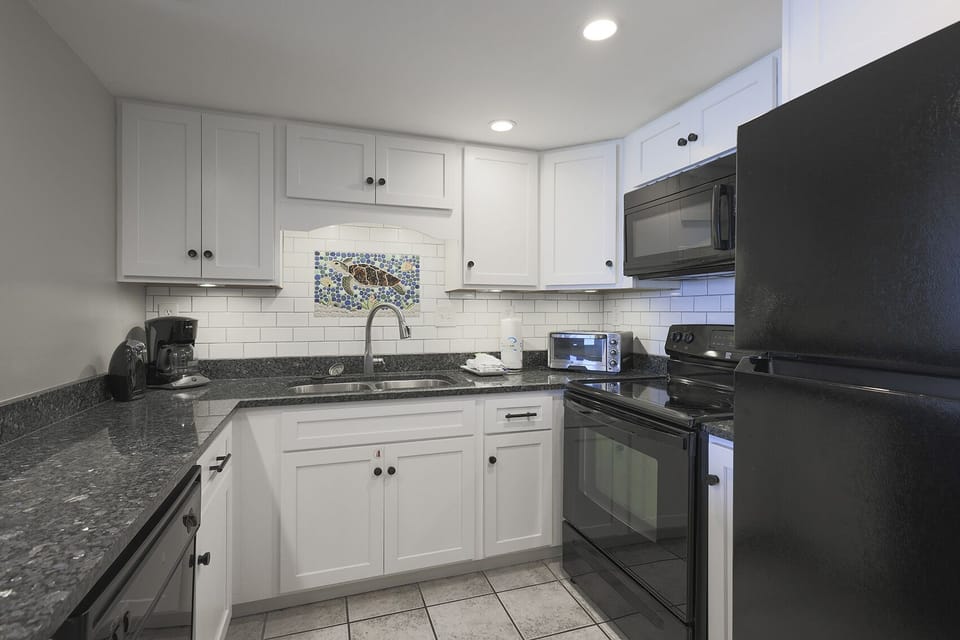 This kitchen features black appliances, granite countertops, and a colorful backsplash, perfect for meal prep and gatherings
