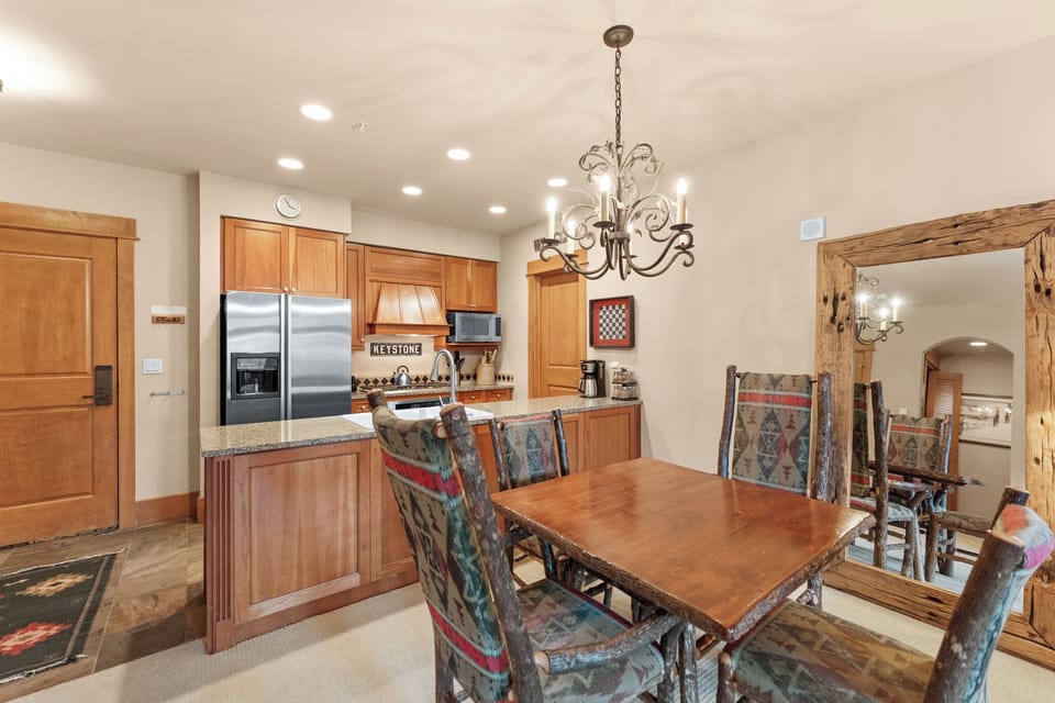 Your open kitchen flows seamlessly into the dining area, where warm wood tones and elegant chandelier lighting create the perfect atmosphere for memorable meals together.