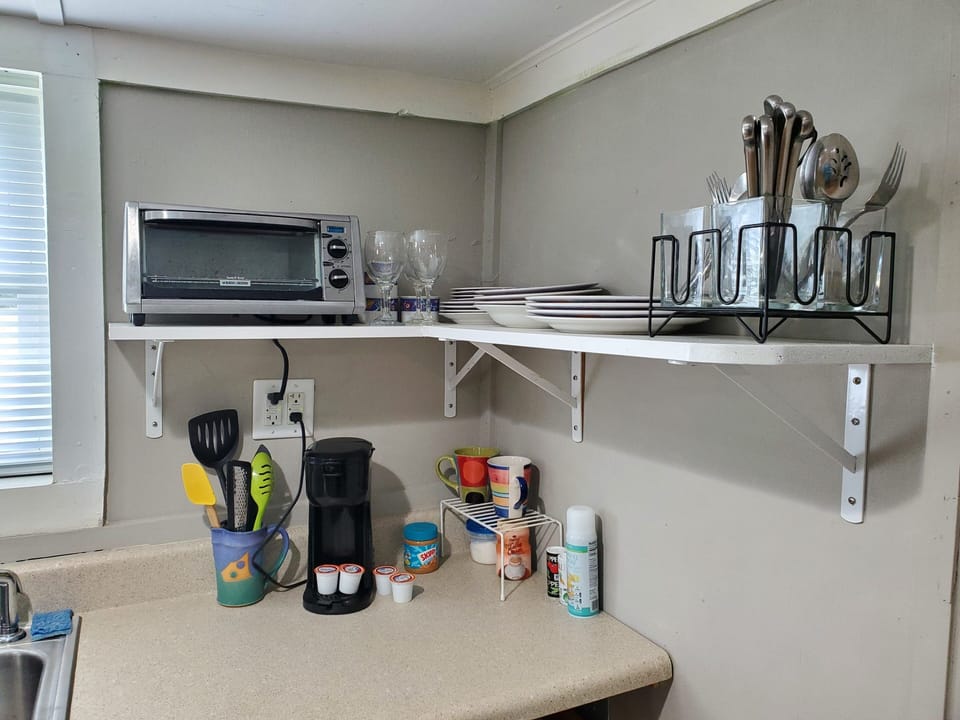 Toaster oven, K-cup coffee maker, dishes, flatware, and cooking utensils. 