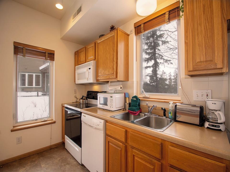 Your fully equipped kitchen features warm wood cabinets, modern appliances, and natural light streaming through windows for delightful meal prep.