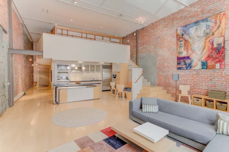 Spacious loft with exposed brick, modern kitchen, and open living area—bright, stylish, and perfect for a comfortable urban stay.