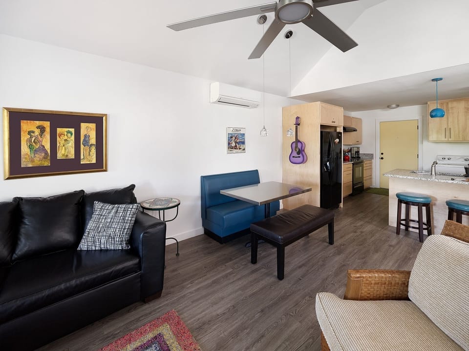 Large comfortable furnishings, excellent modern décor and TV. This view shows the door to the balcony and abundance of natural light.