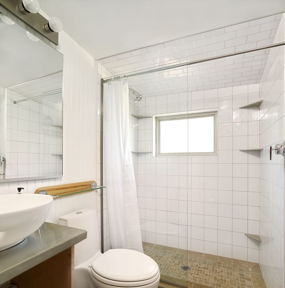 Clean modern tile, beautiful sink, natural light. We provide a starter supply of toilet paper, paper towels dishwasher pods, and conditioning shampoo and shower gel. 