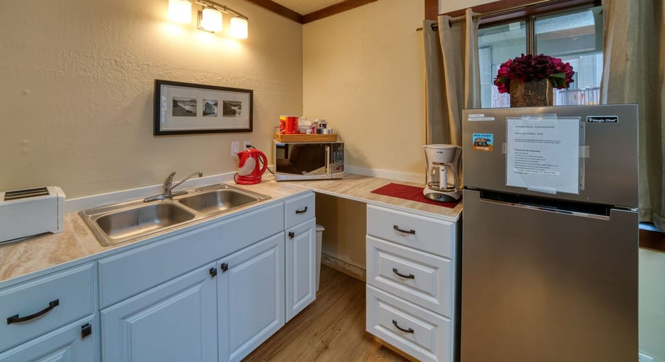 Kitchenette with microwave, toaster, coffee maker, plates, utensils & fridge.