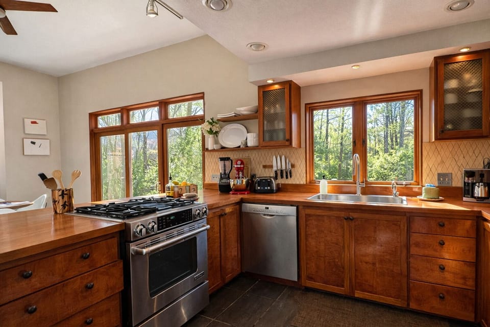 Sunlit, fully equipped kitchen with gas range, dishwasher and forest views