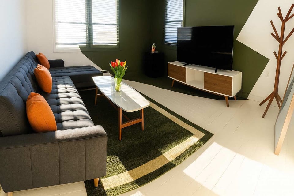 Sunlit living room with modern sectional, bold accents, and cozy rug—stylish, comfortable space ideal for relaxing.
