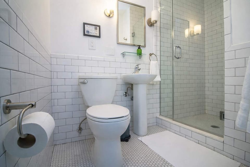 Clean, modern bathroom with classic subway tile, glass shower, and bright finishes—spotless, fresh, and comfortable.
