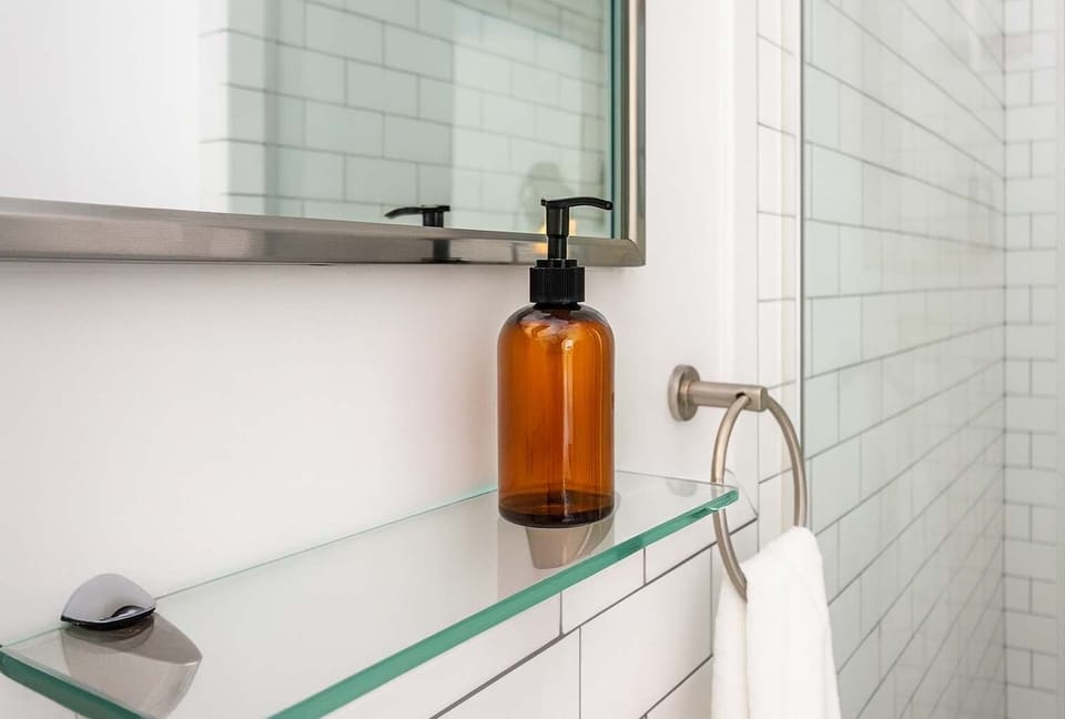 Thoughtfully styled bathroom details with clean lines, glass shelf, and modern fixtures—simple, fresh, and hotel-like.
