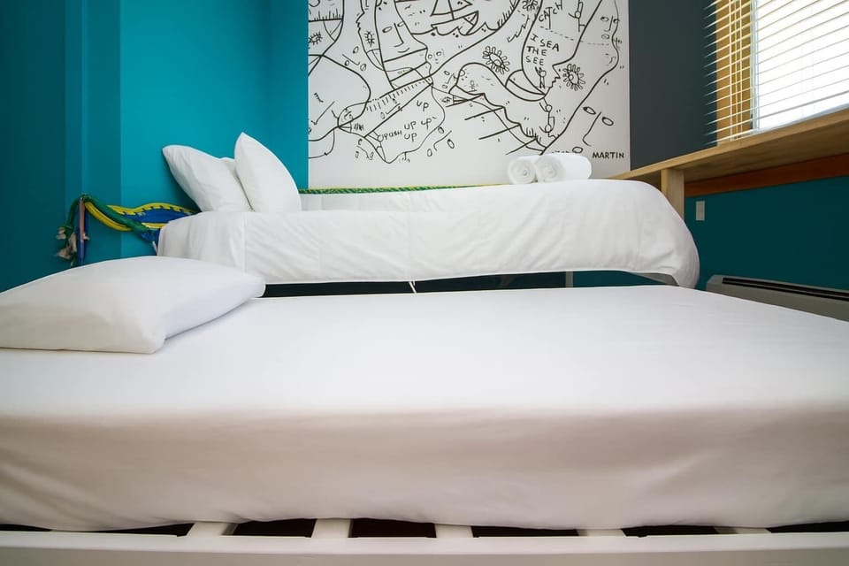 Stylish bedroom with crisp white linens, modern design, and artistic accents—clean, comfortable, and thoughtfully curated.
