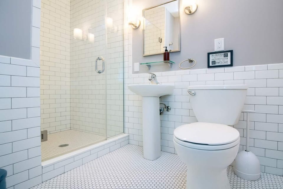 Bright, spotless bathroom with classic subway tile, glass shower, and modern fixtures—clean, fresh, and thoughtfully designed.
