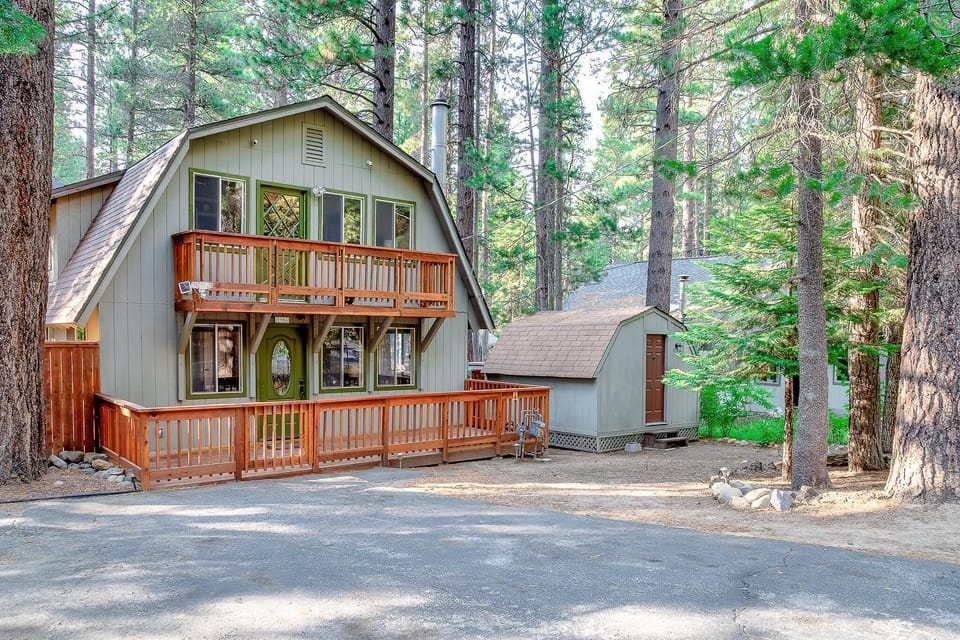 Exterior view of the two-story home with gray siding, green-trimmed windows, and a wooden balcony and ramp.