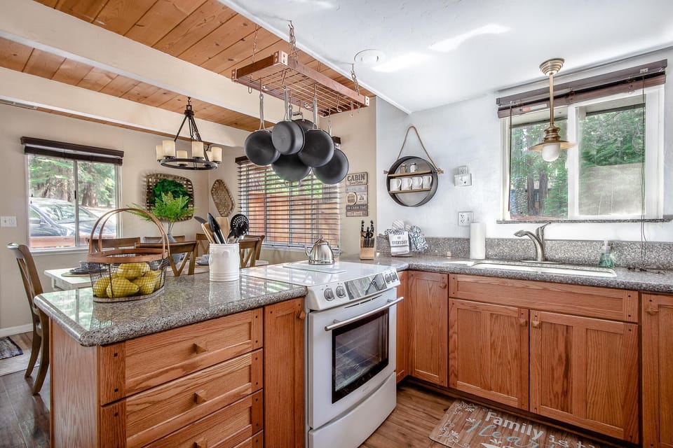 Granite countertops and oak cabinets surround a white stove and stainless steel sink beneath a pendant light.