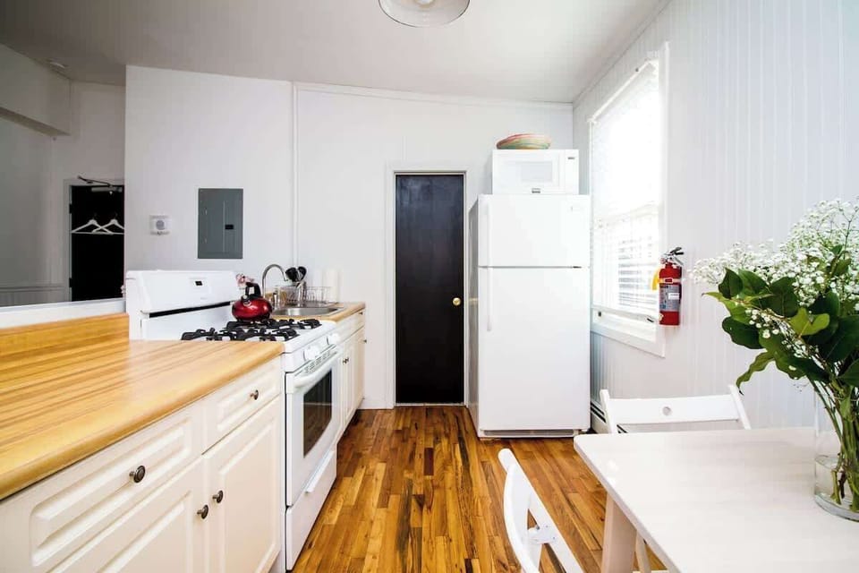 Clean, sunlit kitchen with warm wood counters, full appliances, and a cozy dining area—bright, functional, and welcoming.
