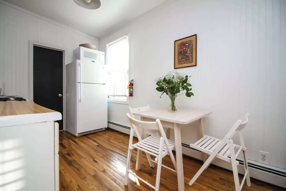 Sunny dining area with cozy seating, warm wood floors, and a welcoming setup—perfect for meals, coffee, or relaxed mornings.
