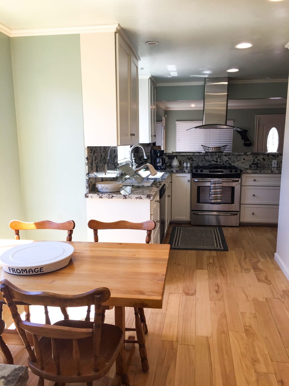 Open living space features kitchen between living & dining areas, wooden floors.