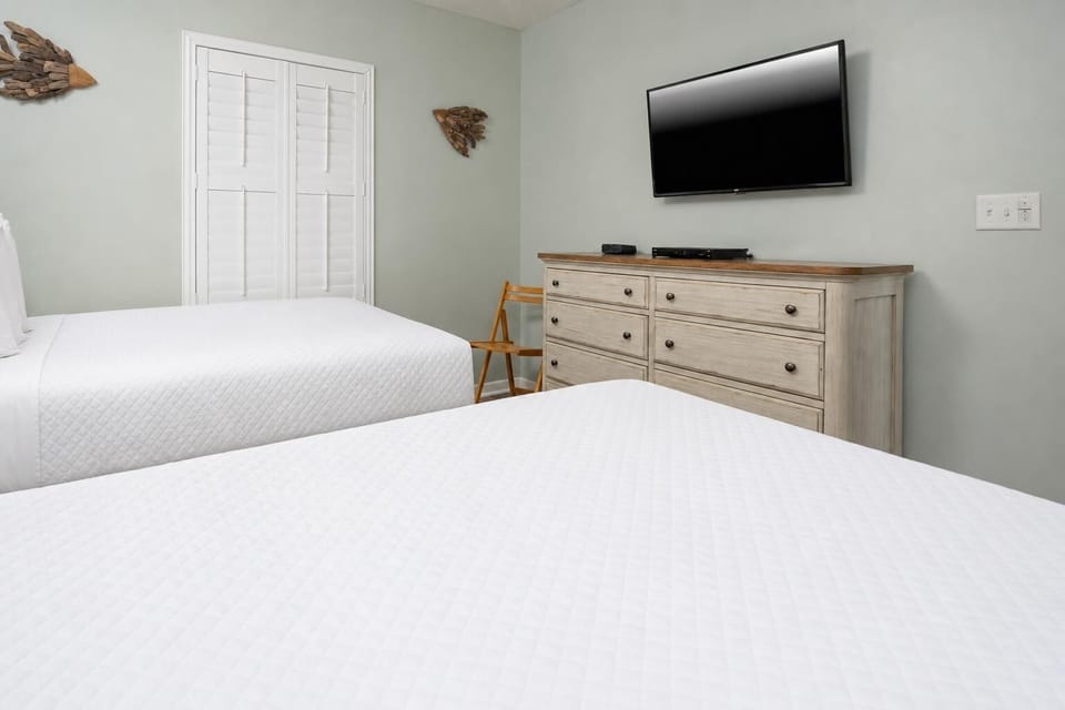 Comfortable guest room featuring two double beds, a dresser, and a TV for your entertainment