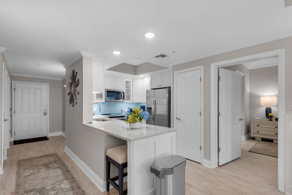 Kitchen with 2 bar stools, pantry, stainless appliances.