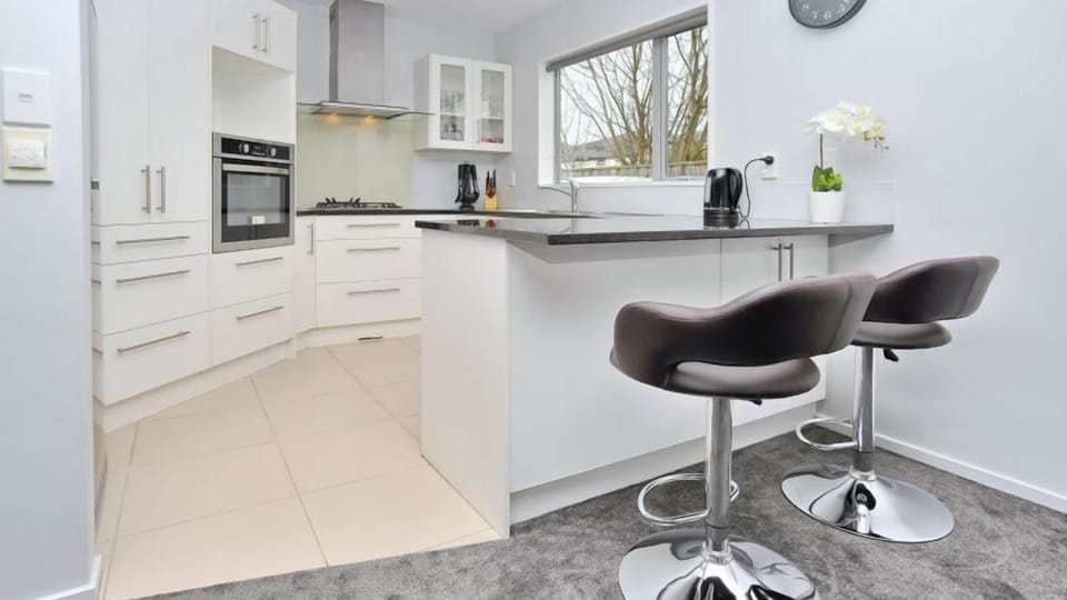 A breakfast bar with stools for the overflow, plus a dishwasher, microwave, filter coffee machine, and air fryer.