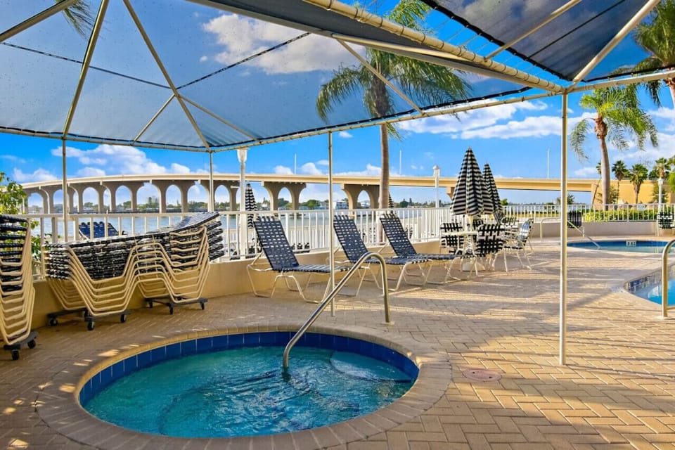 Relax and unwind in the outdoor hot tub, surrounded by comfortable poolside loungers, tropical palm trees, and a welcoming resort-style atmosphere.