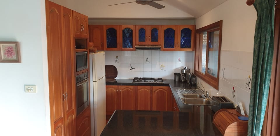 Kitchen with gas hob, oven, fridge, dishwasher, microwave, coffee machine, fan.