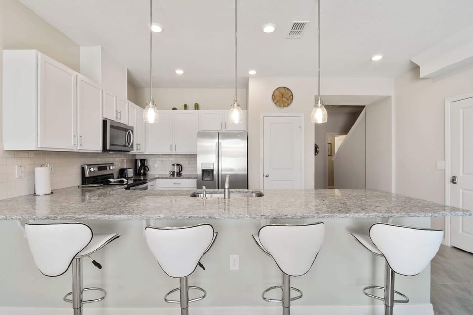 Bright granite island kitchen with pendant lighting and four chic bar stools (seats 4) - modern, airy design with subway-tile backsplash and stainless appliances for social cooking.