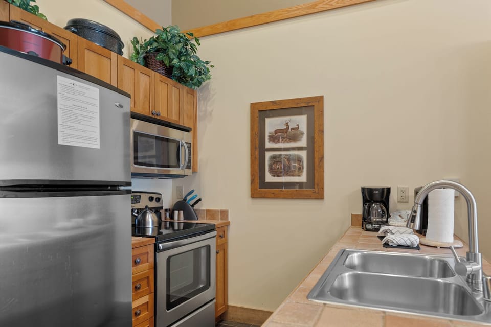 Cook your favorite meals in this fully equipped kitchen featuring stainless steel appliances, warm wood cabinetry, and everything you need for a comfortable stay.
