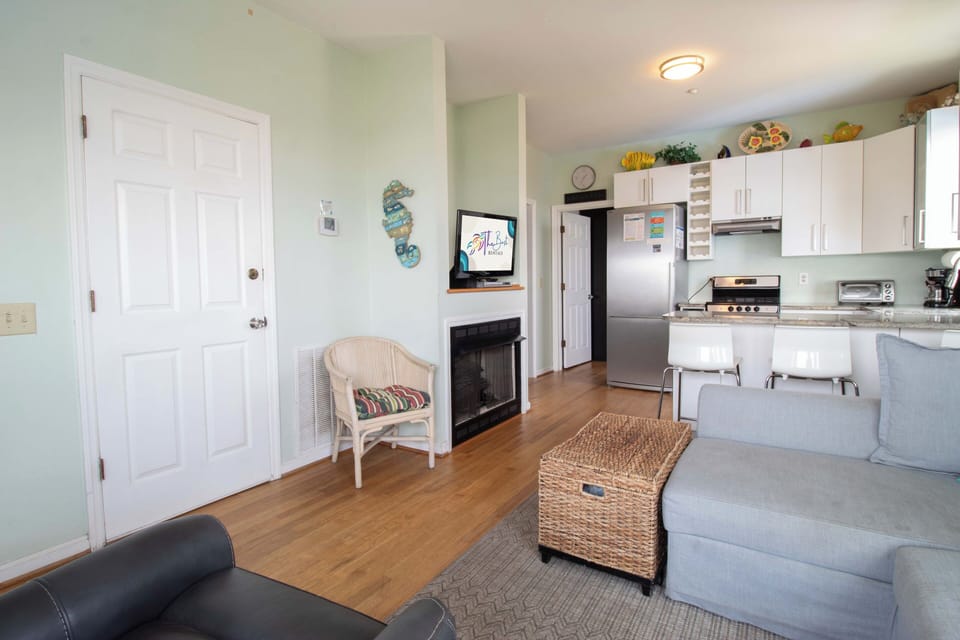 Step into your inviting open-concept retreat, where soft coastal hues and warm wood floors welcome you home. The full kitchen flows seamlessly into your cozy living area, complete with a fireplace for quiet evenings.