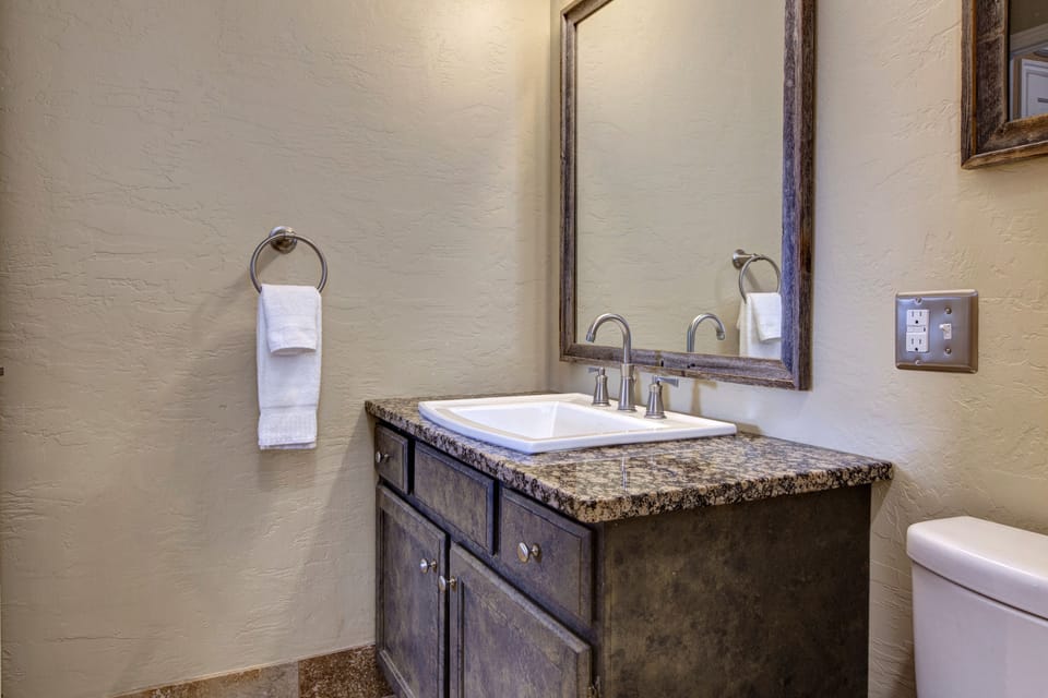 Modern & clean guest bathroom with a sleek vanity, granite countertop, and a shower/tub combo. A practical, stylish space for your visit.