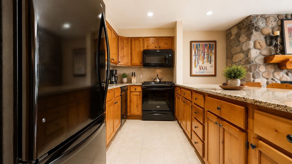 Cook your favorite meals in this fully equipped kitchen with modern appliances, warm wood cabinetry, and charming stone accent wall—your mountain home away from home.